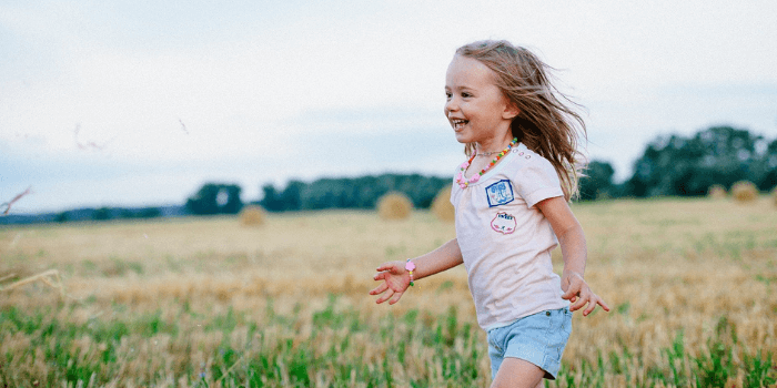 Kind läuft lachend über ein Feld