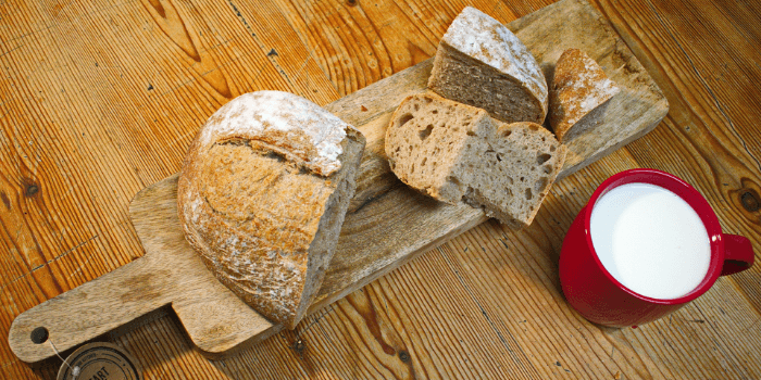 Geschnittenes Brot auf Holzbrett und eine Tasse Milch