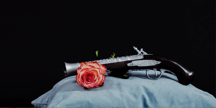 Pistole auf Kissen mit Rose davor