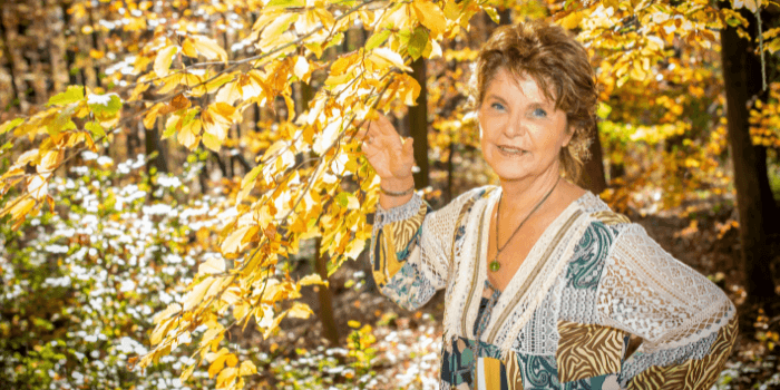 Frau steht unter herbstlichem Baum