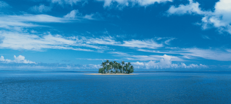 Kleine Insel im tiefblauen Meer mit Palmen unter blauem Himmel