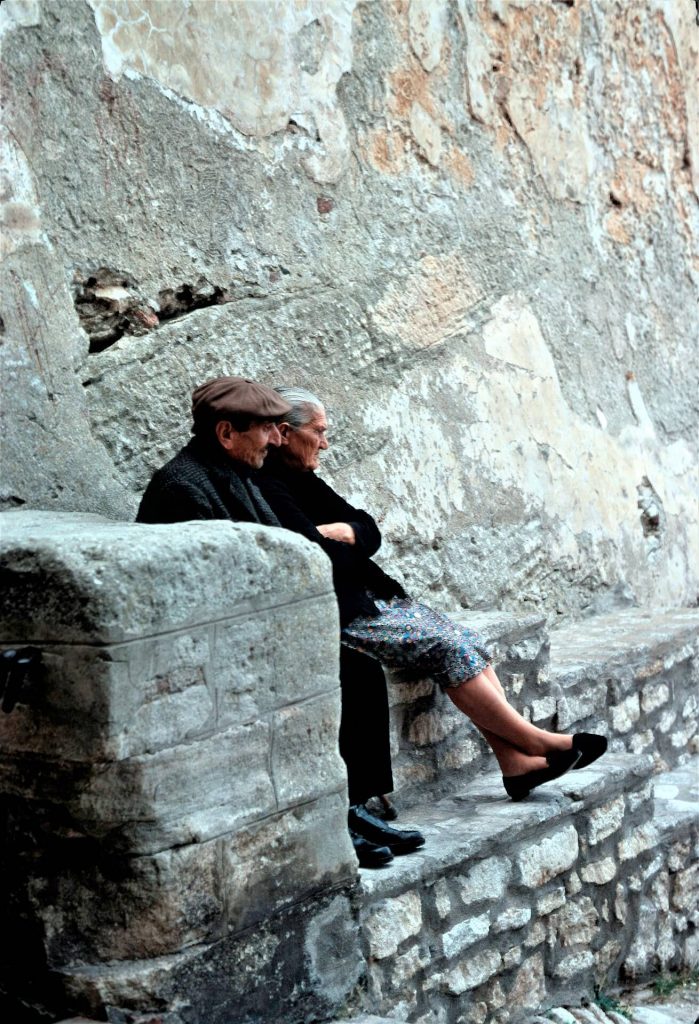Altes Ehepaar auf einer Mauer sitzend