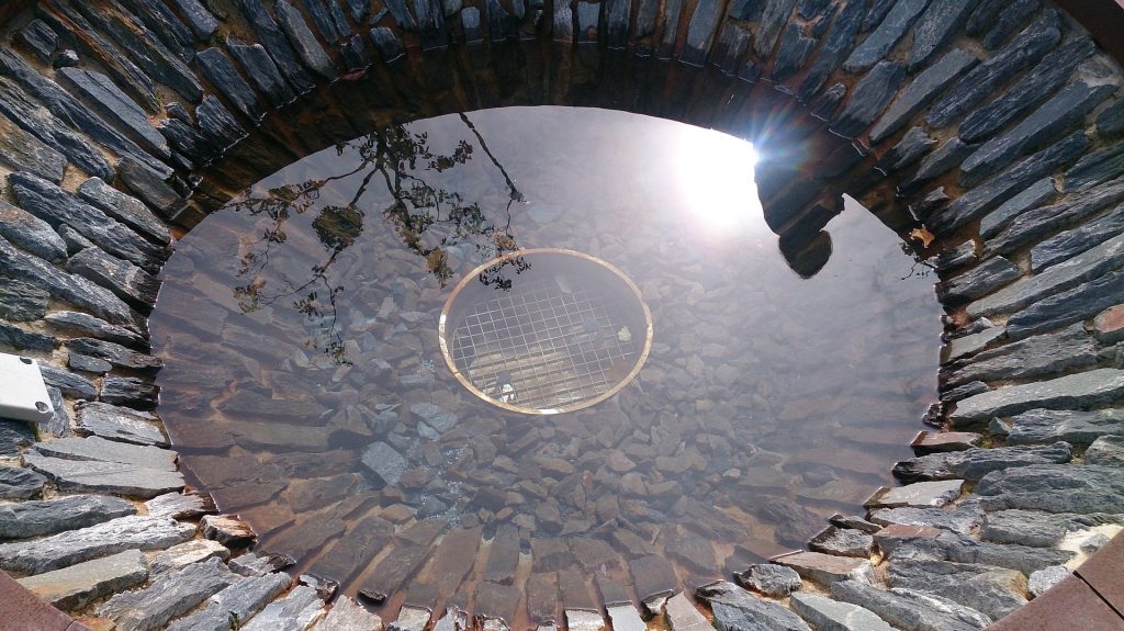 Im brunnen spiegeln sich die Sonne und ein Mensch