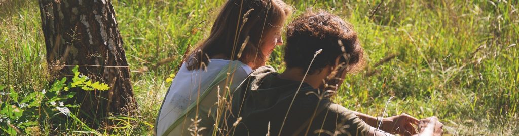 Paar sitzte im Gras und unterhält sich