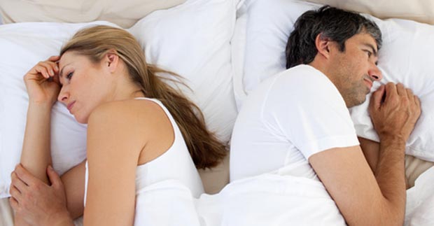 Richtig streiten in Beziehungen: Paar liegt im Bett voneinander abgewandt - Streit