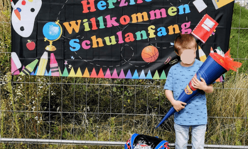 Milo mit Schultüte vor Herzlich willkommen Schild