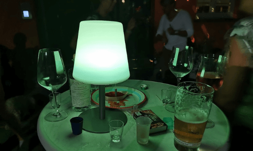 Stehtisch mit Lampe, Gläsern, Wein und Bier