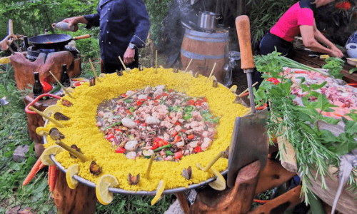Meeresfrüchte-Paella, im Hintergrund der Koch und die Köchin