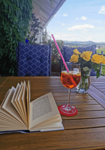 Aperol Spritz und ein Buch auf dem Balkon