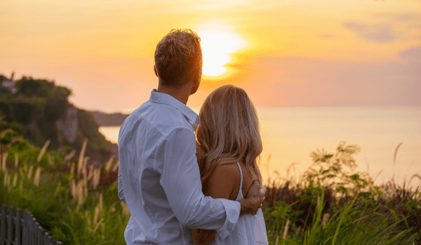 Beziehung retten, Paar schaut sich Sonnenuntergang am Meer an