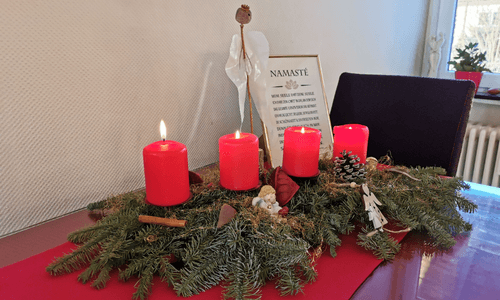 Jahresrückblick 2022, ein Adventskranz mit vier brennenden Kerzen auf dem Tisch und ein Namaste-Bild