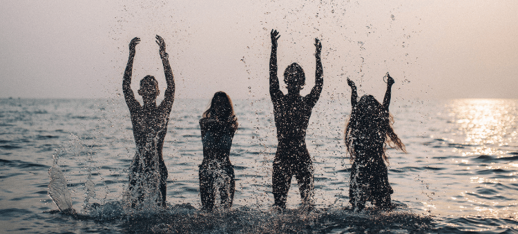 Mindfucks Harmonie - vier Personen stehen im Meer und spritzen Wasser in die Luft