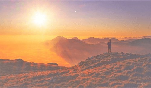 Das Goldene Zeitalter beginnt: Person steht auf Hügel und schaut in die untergehende Sonne