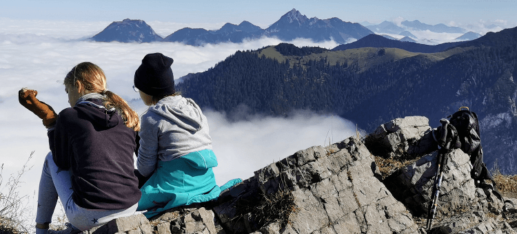 Auf dem Berggipfel sitzen zwei Mädchen und schauen in das vernebelte Tal. Sie haben ihr Ding gemacht