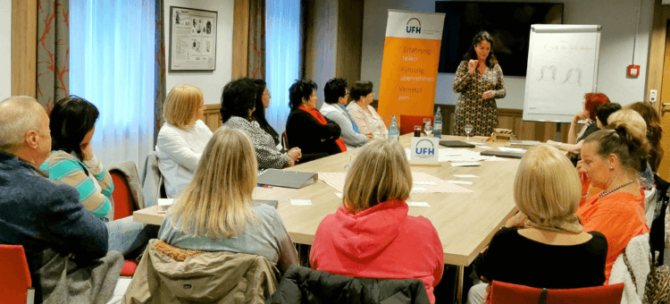 Unternehmerfrauen am langen Tisch. Reverentin vor der Flipchart