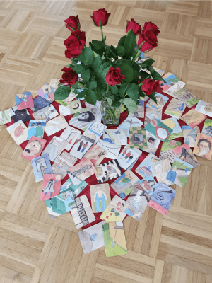 Bildkarten liegen um einen Rosenstrauß herum. Dieser steht auf dem Boden