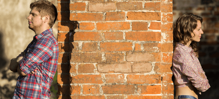 Paar lehnt an Mauer - jeder auf seiner Seite. Ist diese Beziehung noch zu retten?