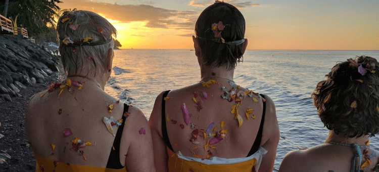 Drei Frauen am Strand von Bali mit Blick in den Sonnenuntergang