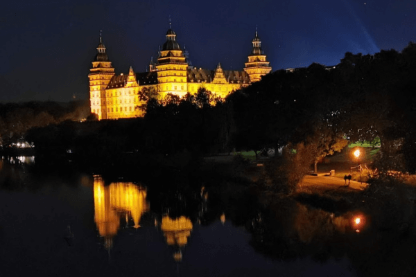 Beleuchtetes Schloss Johannisburg spiegelt sich im Main