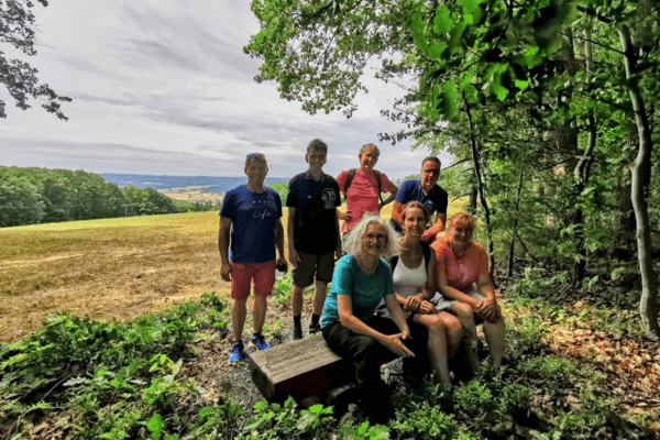 Eine Gruppe von 7 Personen vor einer idyllischen Landschaft