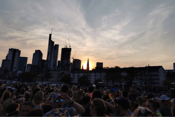 Tanzende Menschen auf einem Schlagerboot. Dieses fährt dem Sonnenuntergang entgegen