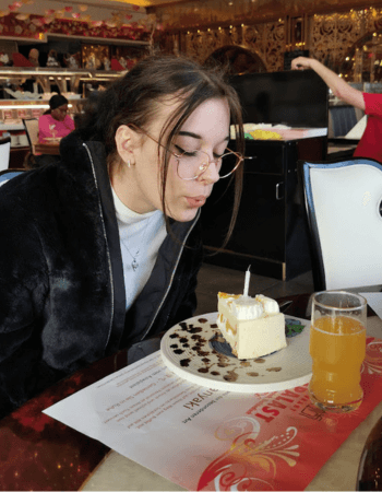 Loona bläst Geburtstagskerze aus, die auf einem Stück Torte steckt