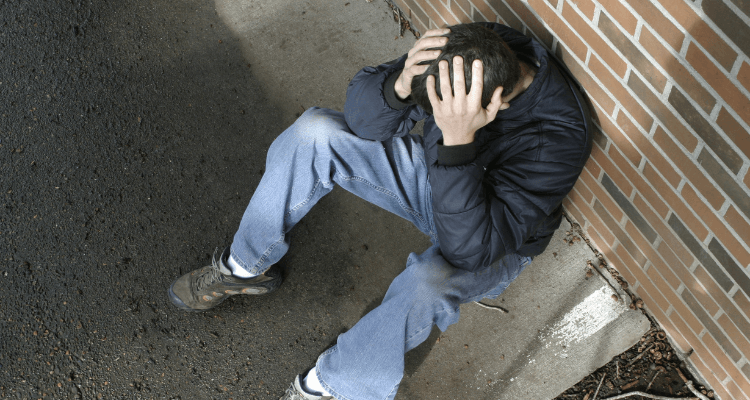 Lebenskrise meistern: Mann sitzt auf dem Boden, Kopf entnervt in den Händen