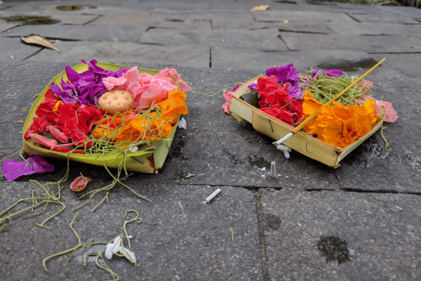 Bali Urlaub anders erleben - Zwei Opferschalen auf dem Boden mit Räucherstäbchen und Blumen
