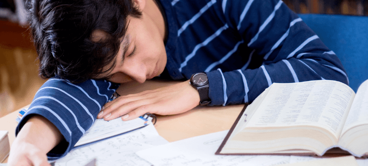 Schüler schläft auf seinen Büchern ein