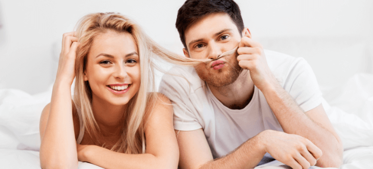 Glückliches Paar auf dem Bauch liegend nebeneinander im Bett