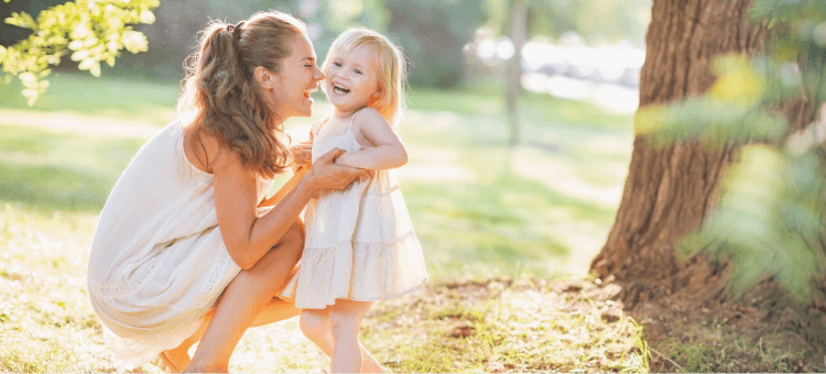 Mutter und kleines Mädchen lachen gemeinsam im Sonnenlicht