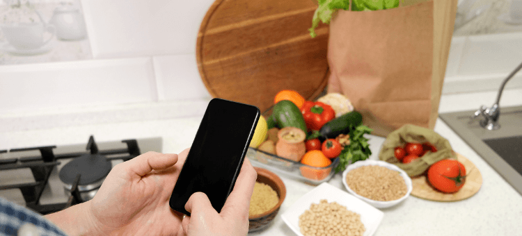 Männerhände mit Smartphone über einem gedeckten Esstisch, während das Essen bereitsteht.